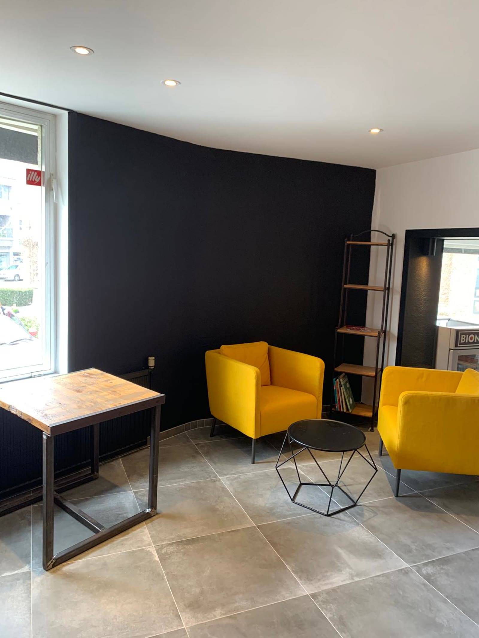 Shop interior with a deep matt black wall and yellow armchairs
